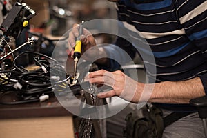 Industrial worker man soldering cables of manufacturing equipment in a factory. Selective focus