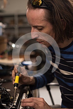 Industrial worker man soldering cables of manufacturing equipment in a factory. Selective focus