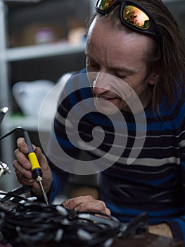 Industrial worker man soldering cables of manufacturing equipment in a factory. Selective focus