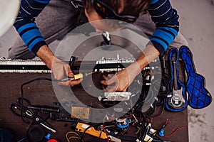 Industrial worker man soldering cables of manufacturing equipment in a factory. Selective focus