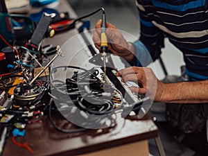 Industrial worker man soldering cables of manufacturing equipment in a factory. Selective focus