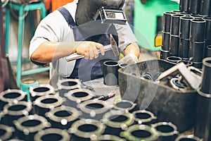 Industrial worker in manufacturing plant grinding to finish a Metal pipe
