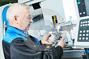 Industrial worker measuring detail near cnc milling machine
