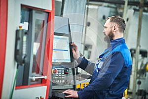 Industrial worker operating cnc machine at metal machining industry