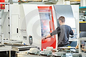 Industrial worker operating cnc machine at metal machining industry