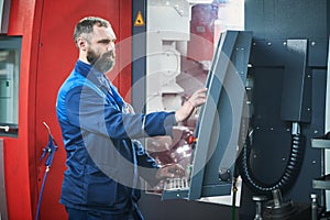 Industrial worker operating cnc machine at metal machining industry