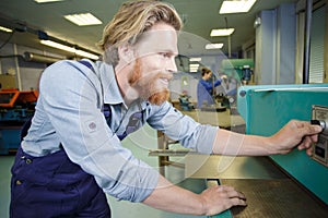 industrial worker operating cnc milling machine in metal machining industry