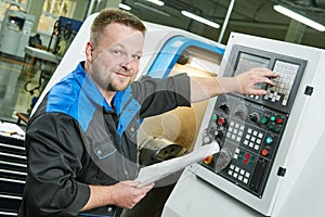 Industrial worker operating cnc turning machine in metal machining industry