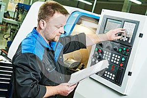 Industrial worker operating cnc turning machine in metal machining industry