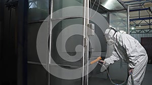 An industrial worker paints metal on a factory production line. A craftsman paints metal doors in production.