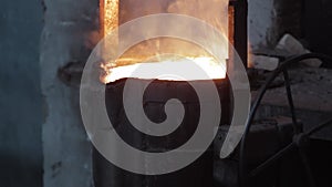 Industrial worker in protective gear pours molten metal at steel foundry. Furnace casting process, hot liquid steel flow