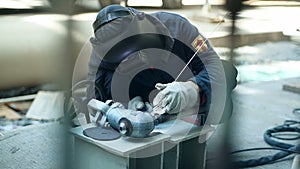 Industrial worker with protective mask welding inox elements in steel structures manufacture workshop.