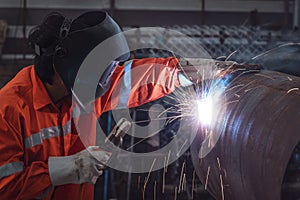 Industrial worker with protective mask welding steel structure in a factory