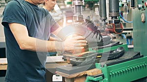 Industrial worker is putting together a boot and its sole