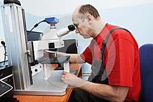 Worker checking probe with industrial microscope photo