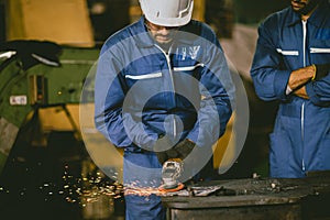 Industrial Worker Using Angle Grinder and Cutting a Metal Sheet. Contractor in Safety Uniform and Hard Hat Manufacturing Metal