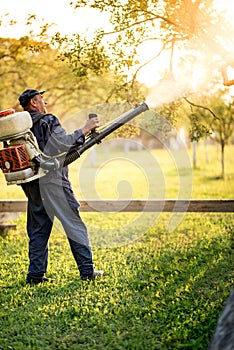 Industrial worker using machine for organic pesticide distribution in fruit orchard