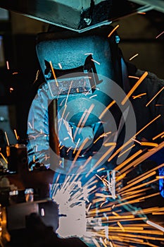 Industrial worker is welding merging automotive part in car factory