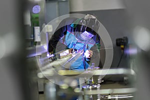 Industrial worker welding in metal factory.