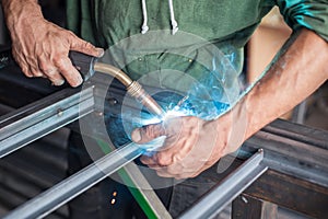 Industrial worker welding the steel structure in the workshop