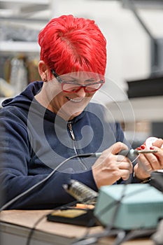 Industrial worker woman soldering cables of manufacturing equipment in a factory