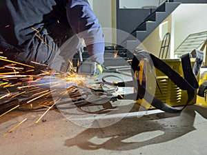 An industrial worker works with metal on an angle grinder.