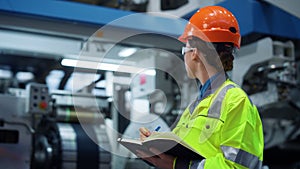 Industrial worker writing project note pad on big manufacture facility closeup