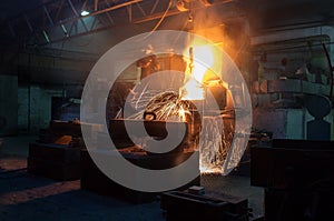 Industrial workers at a foundry pour molten metal with sparks. Teamwork in heavy industry, manufacturing process