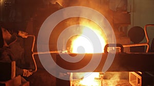 Industrial workers pour molten metal at steel foundry. High-temperature smelting process, heavy industry manufacturing