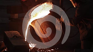 Industrial workers pour molten metal at steel foundry. Safety gear, helmets and face shields protect from intense heat