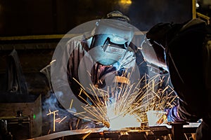 Industrial workers are welding merging automotive part in car factory