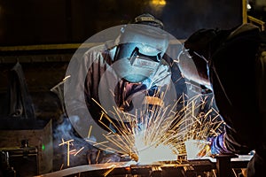 Industrial workers are welding merging automotive part in car factory photo