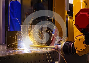 Industrial yellow robot welder welding steel part manual, welding splatter repairman, light weld