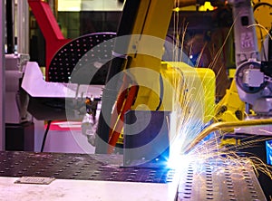 Industrial yellow robot welder welding steel part manual, welding splatter repairman, light weld