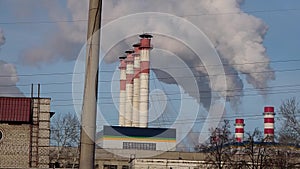 Industrial zone with a large red and white pipe thick white smoke is poured from the factory pipe in contrast to the sun