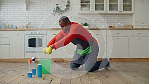 Industrious african male wiping floor at home