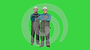 Industry, building, construction and people concept - happy male builders on a Green Screen, Chroma Key.