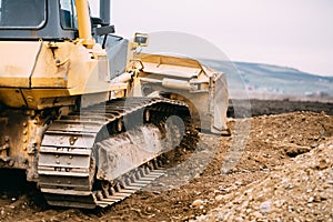 Industry details - road construction site yellow bulldozer levelling and moving soil during highway building photo