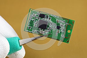 IT industry engineer holds with tweezers mini wireless bluetooth  module for mobile devices macro