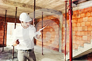 Industry engineer working on site, man reading paper plans and supervising works