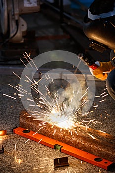 Industry safety working concept. Welder holding a steel welding machine weld piece of metal in a factory at night time. Nice bokeh