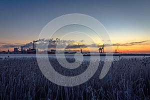 Industry with smoke chimneys and nature reed landscape in sunrise