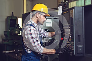 Industry Worker entering data in CNC machine at factory.