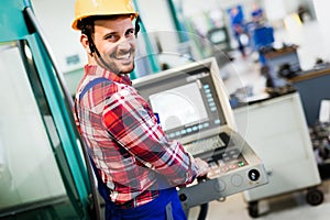 Industry Worker entering data in CNC machine at factory