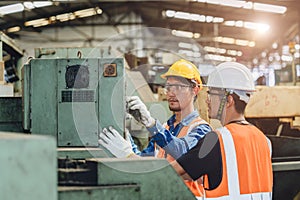 Industry worker working together training young new machine operator staff in metal factory