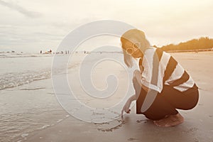 Indy asian women smile draw heart shape on sand beach
