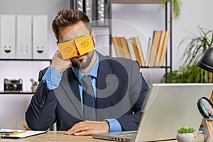 Inefficient tired lazy business man working sleeping on laptop computer with eyes stickers on face