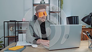 Inefficient tired lazy businessman working sleeping on laptop computer with eyes stickers on face