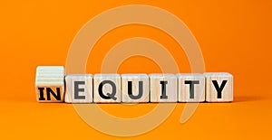 Inequity or equity symbol. Turned wooden cubes and changed the concept word Inequity to Equity. Beautiful orange table orange