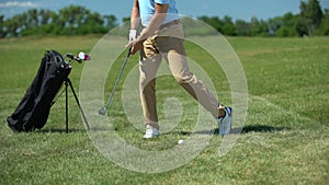 Inexperienced rich man hitting past golf ball displeased with failed shot, loser